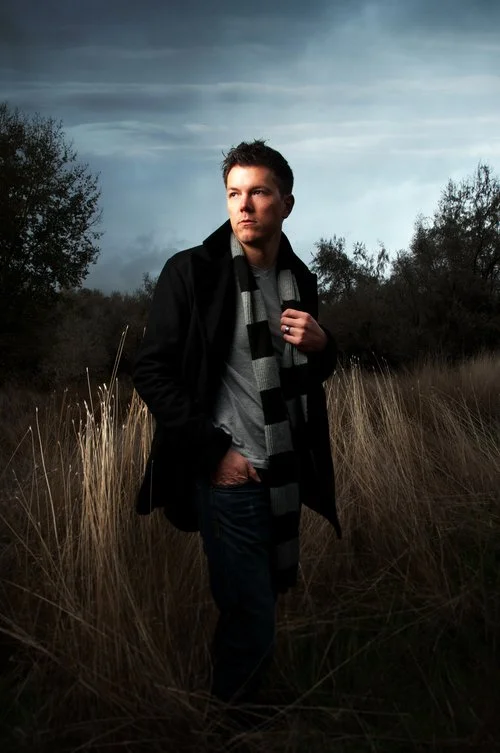Jon Jensen standing in a field of dry grass under a dark sky